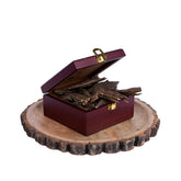 A wooden box with a gold clasp containing agarwood sticks, placed on a wooden disc.