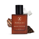 A bottle of Zodiaura Magic Potion perfume with a brown tint and a label featuring the brand name and product title. The bottle is accompanied by a white flower and a piece of wood, suggesting the earthy and woody fragrance notes.